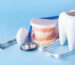 dental-health-teethcare-concept-dental-mirror-with-explorer-probe-toothbrush-floss-human-jaw-model-white-tooth-with-stethoscope-blue-background_136401-4117
